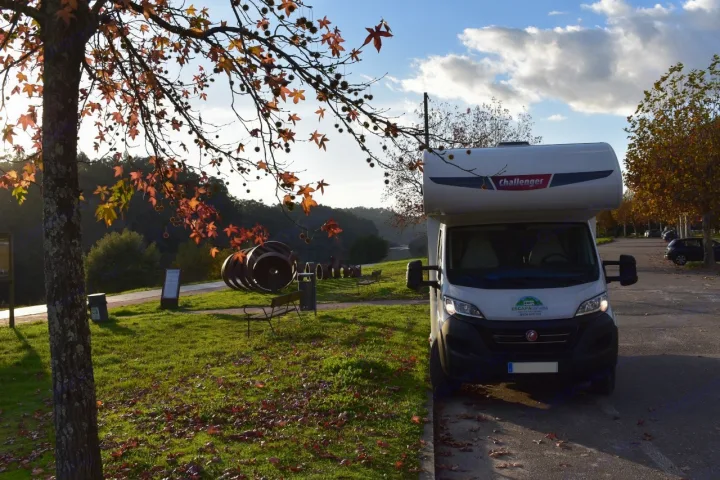 White Challenger RV rental parked in an autumn park. Foreground tree with orange leaves, grassy area with benches, distant water.. CHALLENGER C194 START EDITION 2026