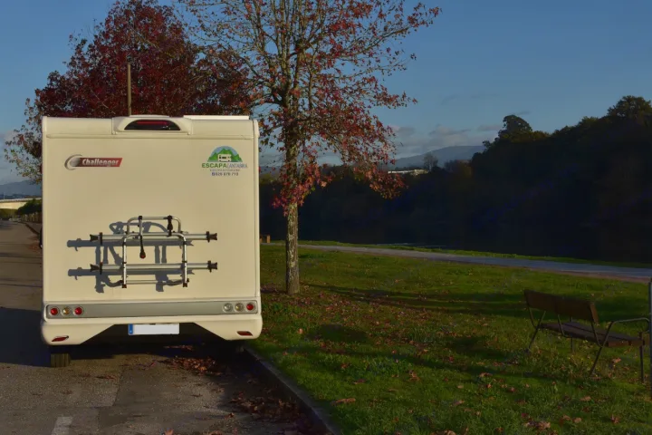 Rear view of a white Escapa Cantabria rv rental with bike rack, parked by autumn trees. Scenic river/hills in background.. CHALLENGER C194 START EDITION 2026