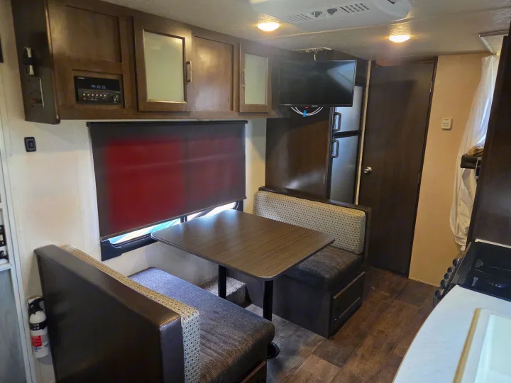 RV rental interior featuring a cozy dinette, mounted TV, and partial kitchenette setup, ready for your next adventure.. Forest River Salem Cruise Lite 2018