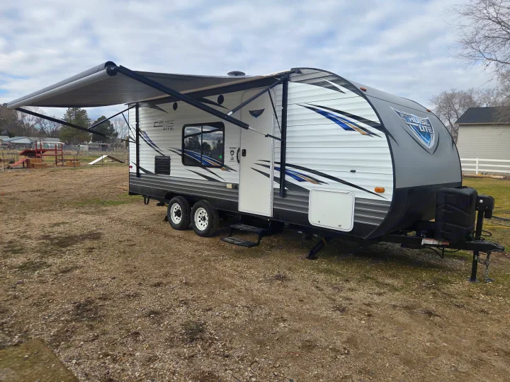 White and gray travel trailer with extended awning, ready for your rv rental adventure or camping trip.. Forest River Salem Cruise Lite 2018