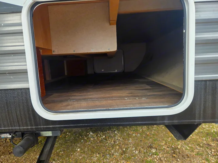 RV rental: Spacious open storage compartment with wood-look floor and internal shelving. Stabilizer jack visible.. Forest River Salem Cruise Lite 2018