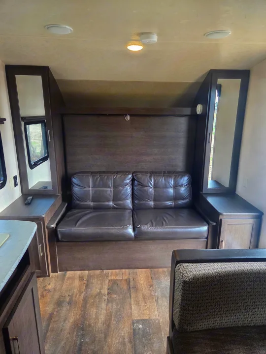 **rv rental** interior: a cozy living area with a brown sofa, wood-look cabinets, and dinette seating. Ideal for your travels.. Forest River Salem Cruise Lite 2018