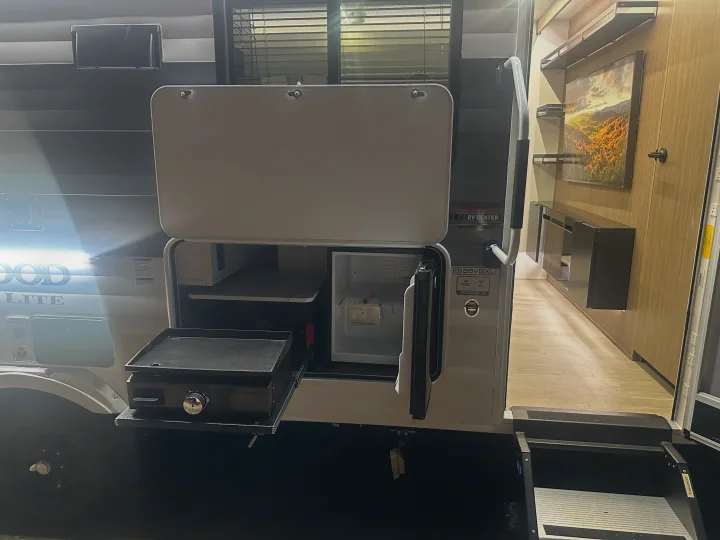 This RV rental offers an outdoor kitchen with a pull-out griddle and mini-fridge for convenient camping.. Forest River Wildwood X-Lite 28VBXL 2026