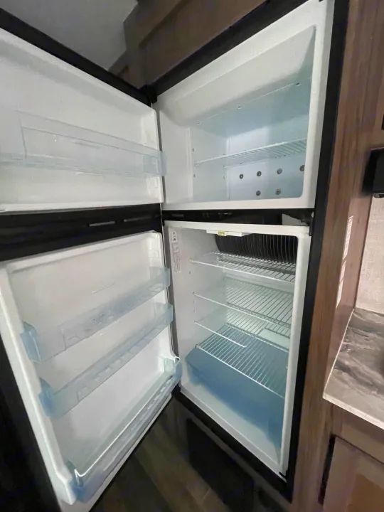 Inside a spacious RV rental refrigerator and freezer, showcasing its clean interior and ample storage for your journey.. Gulf Stream Friendship 2022