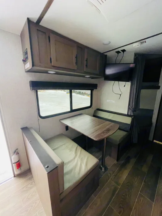 RV rental interior features a dinette, overhead cabinets, TV, window, bunk beds, and a fire extinguisher.. Gulf Stream Friendship 2022