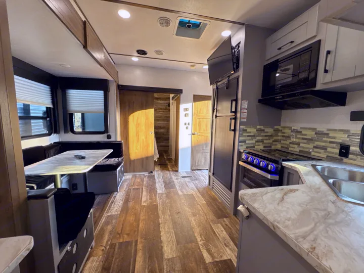 This spacious rv rental features a modern kitchen with a stove, microwave, fridge, a dinette, and wood-look flooring.. Keystone RV Fuzion Toy Hauler 2020