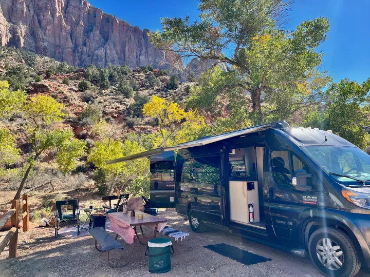 RV rental set up for glamping amidst stunning red rock mountains and vibrant autumn foliage at a scenic campsite.. Pleasure-Way Pleasure-Way Class B 2020