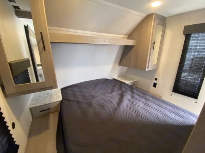 Cozy RV rental bedroom interior with a comfortable bed, overhead cabinets, and nightstands. Perfect for your next adventure.. Coleman Lantern 2021