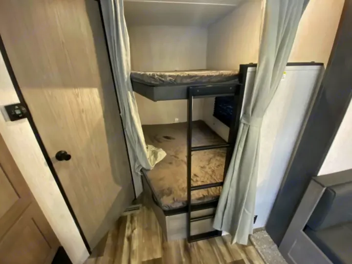 RV rental interior: Comfortable bunk beds with ladder & privacy curtains for cozy travel adventures.. Coleman Lantern 2021