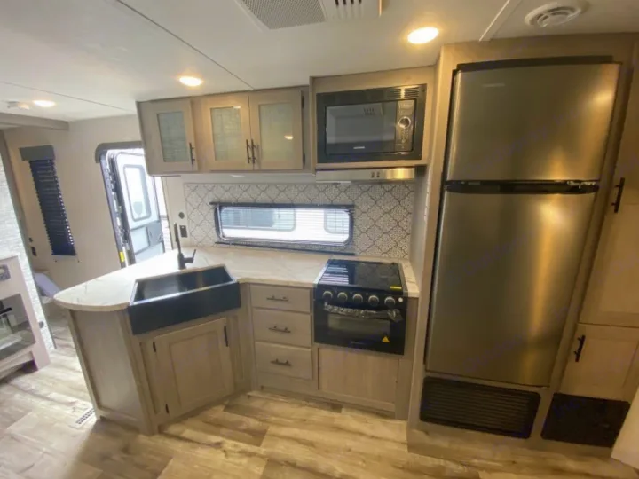 Modern RV rental kitchen featuring a large black sink, stainless steel appliances, and ample counter space.. Coleman Lantern 2021