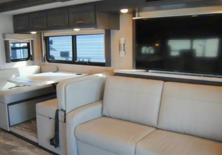 RV rental interior: a bright living space with a dinette, comfy sofa, and TV for relaxing on the road.. Thor Challenger 2023