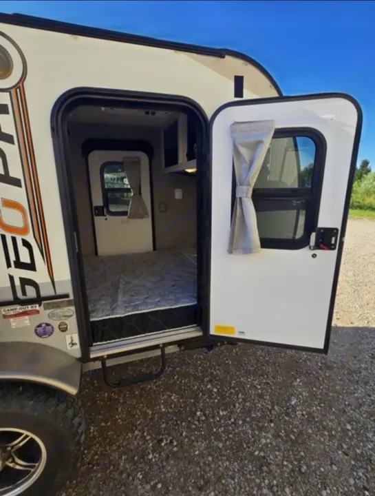 This RV rental's open door shows a small camper's interior, featuring a mattress and an inner door.. Forest River Rockwood Geo Pro 2018