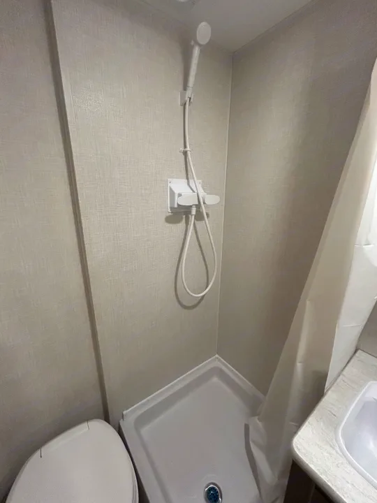 RV rental bathroom: compact design with a toilet, handheld shower, and a small sink, ideal for travel.. K-Z 130RD 2026