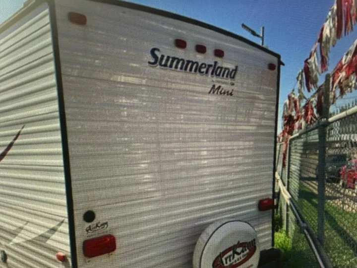 Rear of a white Summerland Mini RV with a visible spare tire, likely at a dealership, ideal for your next rv rental.. Springdale Sumerland mini 2015