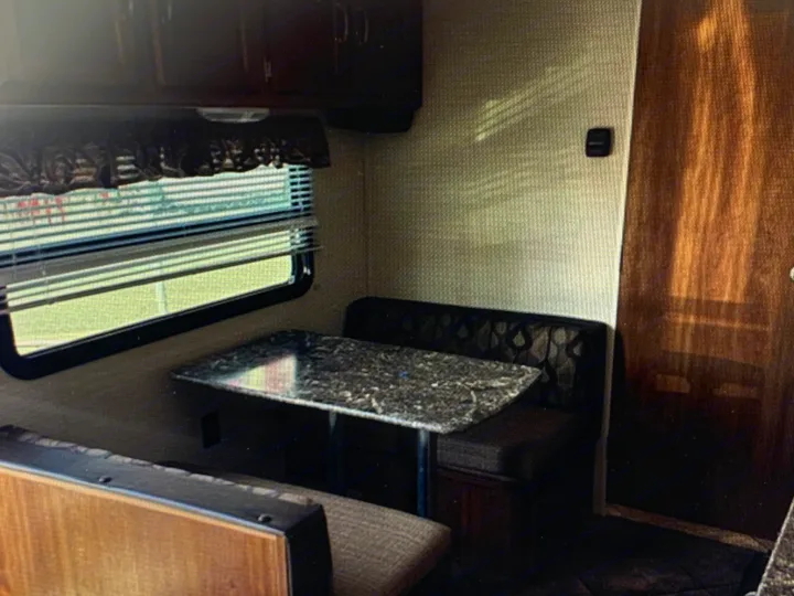 RV rental dinette area. Cozy camper interior with table, benches, and window blinds.. Springdale Sumerland mini 2015