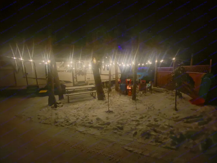 Enjoying a snowy night at an RV rental campsite with warm string lights and a crackling campfire.. Crossroads RV Sunset Trail Super Lite 2023