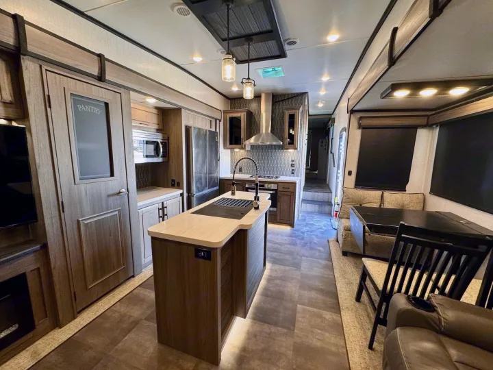 Spacious RV rental interior featuring a modern kitchen with island, pantry, dining area, and comfortable living space.. Crossroads RV Cameo 2021