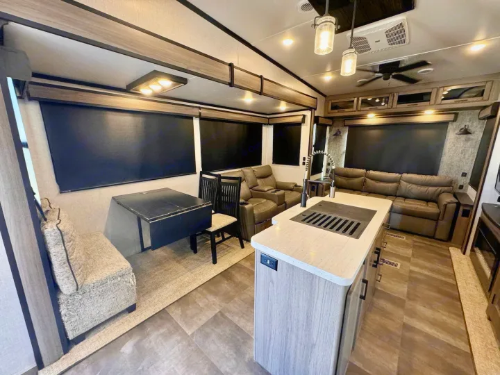 Cozy rv rental living and kitchen space, featuring recliners, dining booth, and island. Ideal for road trips.. Crossroads RV Cameo 2021