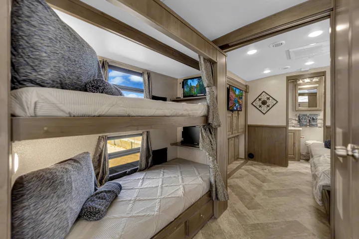 Cozy RV rental interior featuring bunk beds with individual TVs, windows, and an adjacent bathroom.. Forest River Georgetown 2019
