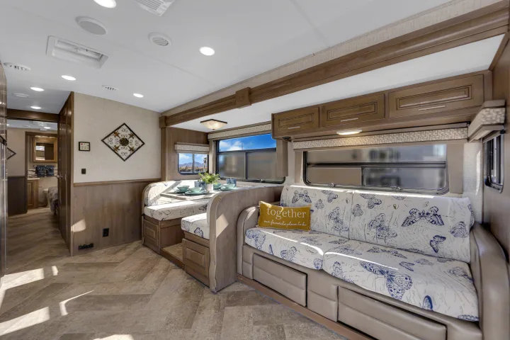 Spacious RV rental interior with a cozy dinette, butterfly-patterned sofa, and wood accents, perfect for travel comfort.. Forest River Georgetown 2019