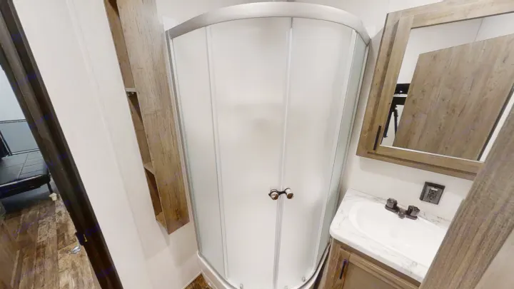 Compact RV rental bathroom: corner shower, vanity with sink, and mirrored cabinet.. Forest River Cherokee Wolf Pack 2021