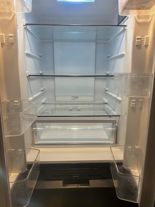 Spacious & clean empty refrigerator in an RV rental, featuring glass shelves, door bins, and a crisper drawer.. Forest River Campsite Reserve 26CJ 2025