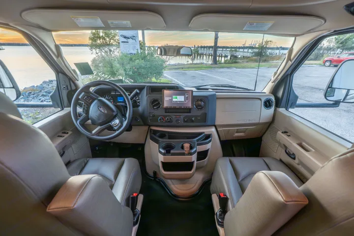 Spacious RV rental cockpit with a Ford dashboard, Android Auto display, and a scenic water view. Perfect for your next trip!. Entegra Coach Odyssey 2023