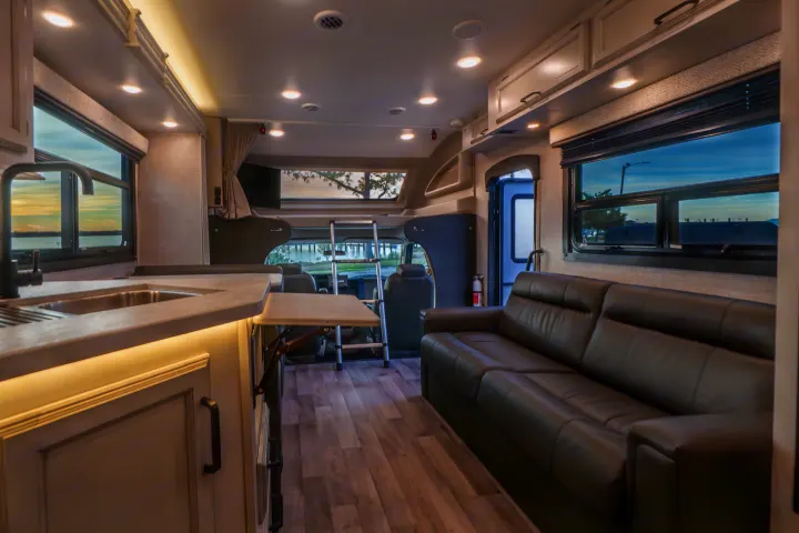 Spacious RV rental interior with a modern kitchen, comfy sofa, and overhead bunk, perfect for comfortable travel.. Entegra Coach Odyssey 2023