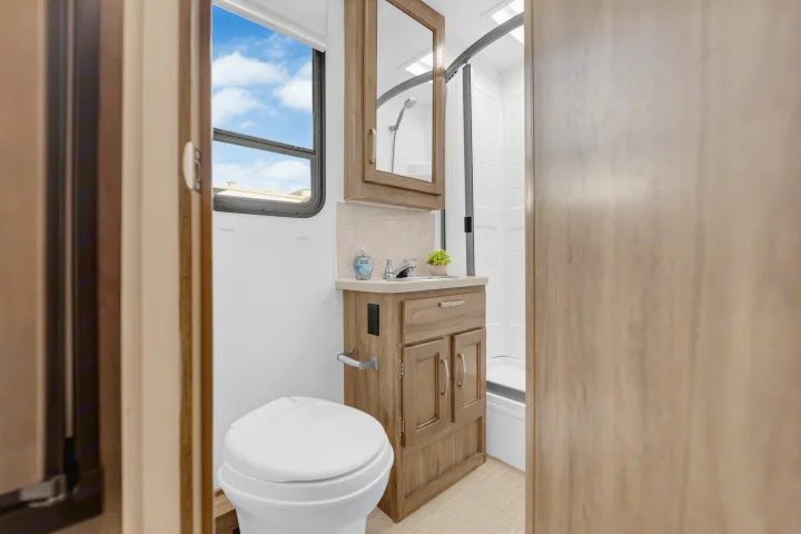 Modern RV rental bathroom with toilet, sink, mirror, and compact shower, perfect for comfortable travels.. Jayco Redhawk 2021