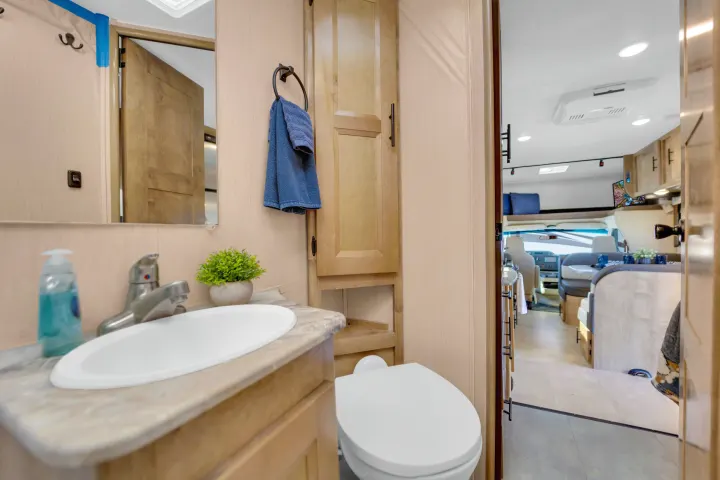 RV rental: functional bathroom with sink, toilet, and a clear view of the cozy main cabin interior.. Coachmen Leprechaun 2021