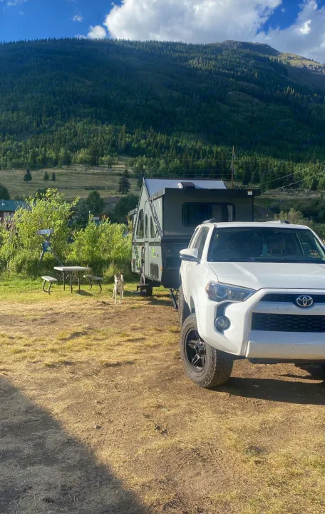 White 4Runner towing an RV rental pop-up camper, with a dog at a scenic mountain campsite.. A Liner A Liner Popup Trailer 2023