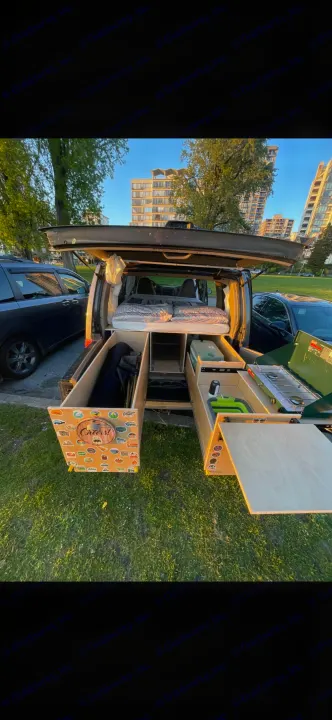 Rear view of a camper van conversion with a cozy bed and pull-out kitchen. Perfect for an RV rental outdoor adventure!. Chevrolet Astro 1999