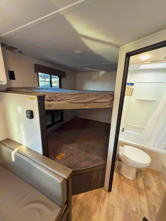 RV rental interior: comfy bunk beds, small couch, and compact bathroom with toilet and shower.. Keystone Hideout 2022