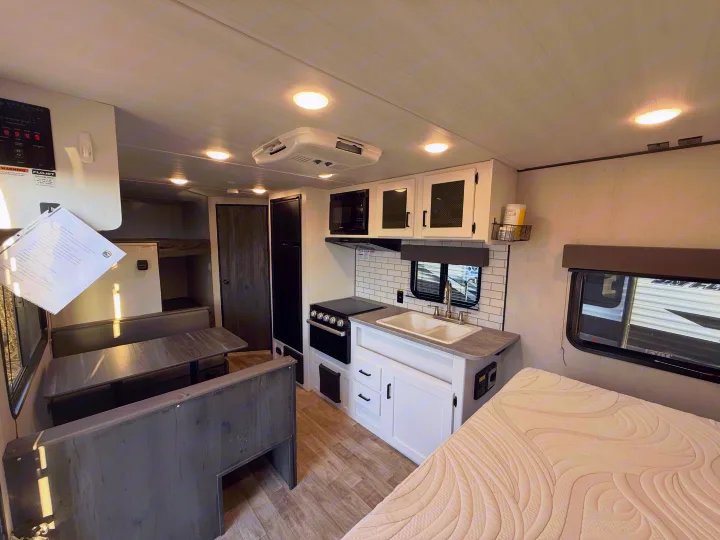 Inside an RV rental: full kitchen, dinette, and bed. Enjoy comfort on the road with this travel trailer camper.. Keystone Hideout 2022