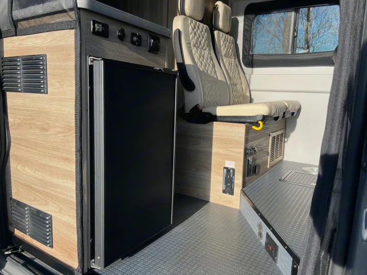 RV rental interior featuring a compact kitchenette with a built-in fridge, cozy seating, and durable flooring for travel.. Winnebago Solis 2025