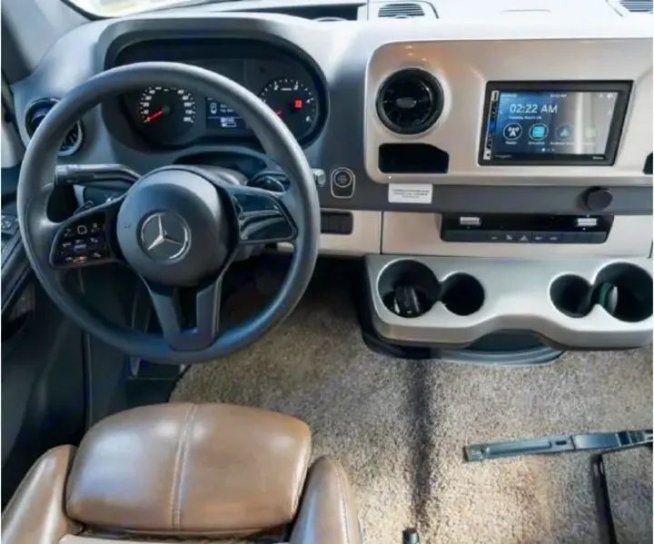 Modern Mercedes-Benz RV rental cockpit with steering wheel, dashboard, infotainment, and cup holders. Clean interior view.. Thor Quantum 2021