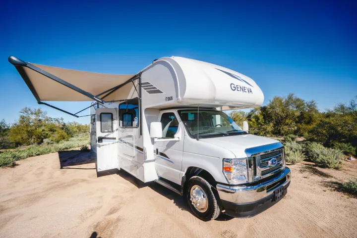 White Geneva rv rental parked in a sunny desert landscape with its awning out, perfect for your next outdoor adventure.. Thor Geneva 2025