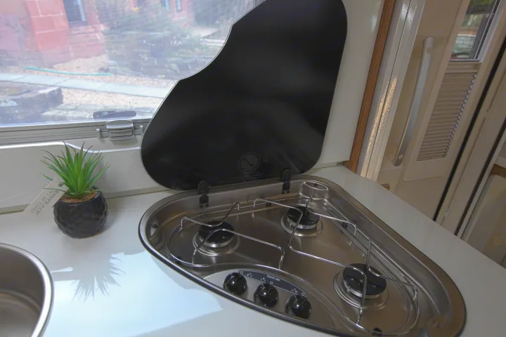 RV rental kitchen: Compact 2-burner Thetford hob, sink, and open glass lid for convenient camper cooking.. rollerteam 747 2021