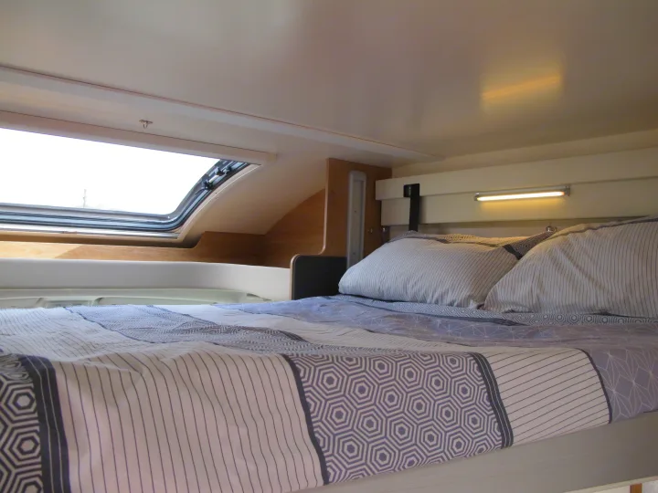 Cozy RV rental bedroom with patterned bed, pillows, and a large roof window. Perfect sleeping area for travel.. rollerteam 747 2021