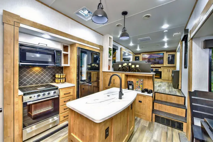 Bright and modern RV rental interior featuring a fully equipped kitchen with island, coffee station, and a tiered living room with large TV.. Heartland RVs Milestone 2023
