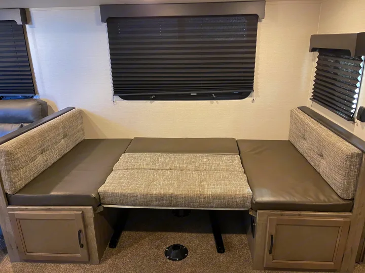Cozy RV rental dinette with convertible table and plush seating, perfect for meals on the road or a comfortable bed.. Coachmen Apex 2021