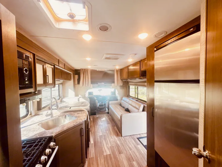 Spacious RV rental interior featuring a full kitchen, comfortable living area, and driver's cockpit. Perfect for road trips.. Thor Four Winds 2022
