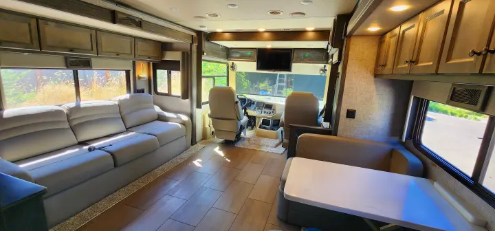 Modern RV rental interior with comfortable sofa, dining booth, and cockpit, featuring wood floors and ample natural light.. Allegro Allegro Open Road 2023