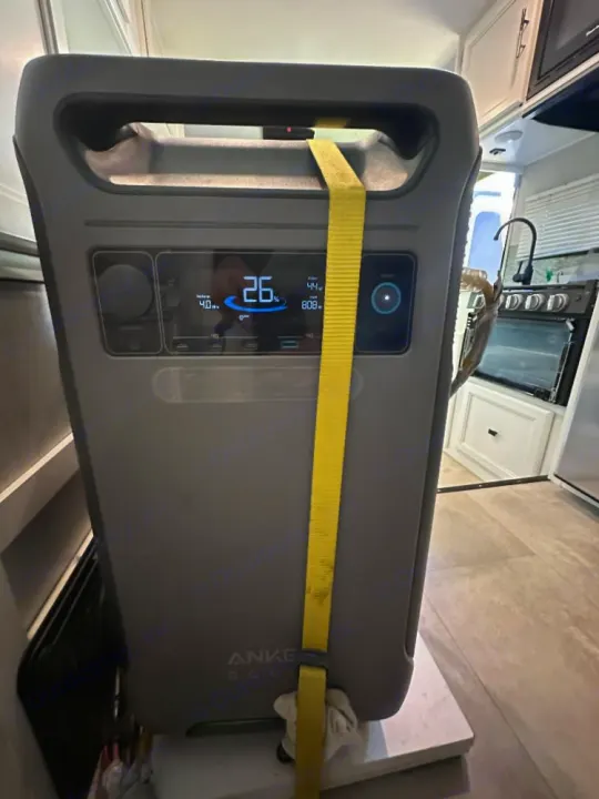 A gray Anker Solix portable power station shows 26% battery, strapped down in an RV rental for portable power.. Coachmen Crosstrek 23XG 2021