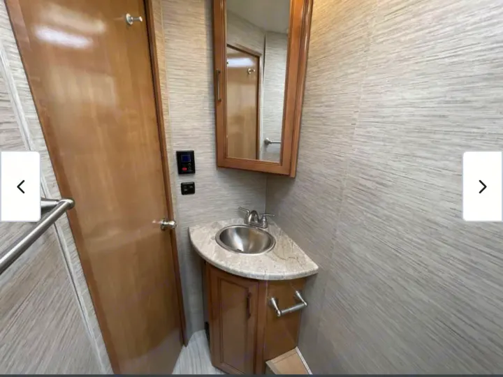 Explore this RV rental's compact bathroom with a corner sink, vanity, mirror, and textured walls.. Thor Quantum 2021