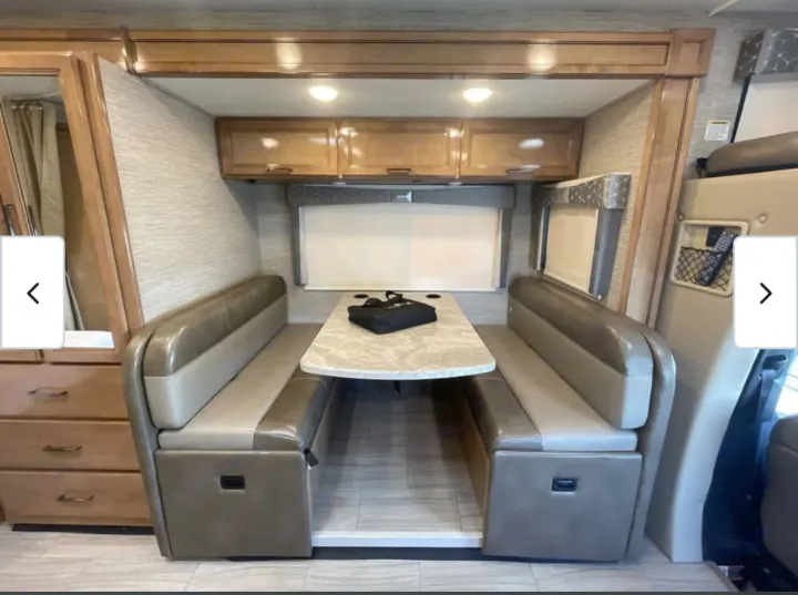 RV rental dinette with comfortable booth seating, central table, overhead storage, and window. Ideal for road trip dining.. Thor Quantum 2021