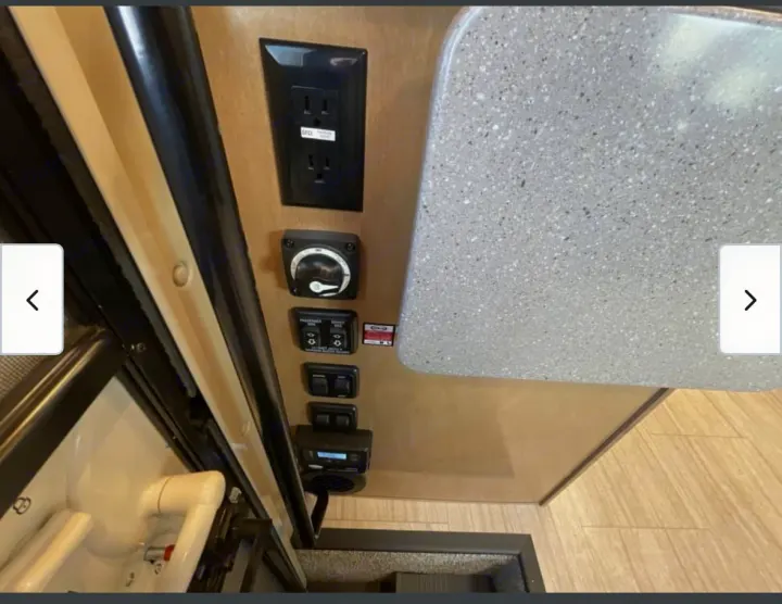 RV rental interior featuring a countertop, GFCI power outlet, and stacked controls for vehicle functions and comfort.. Thor Quantum 2021