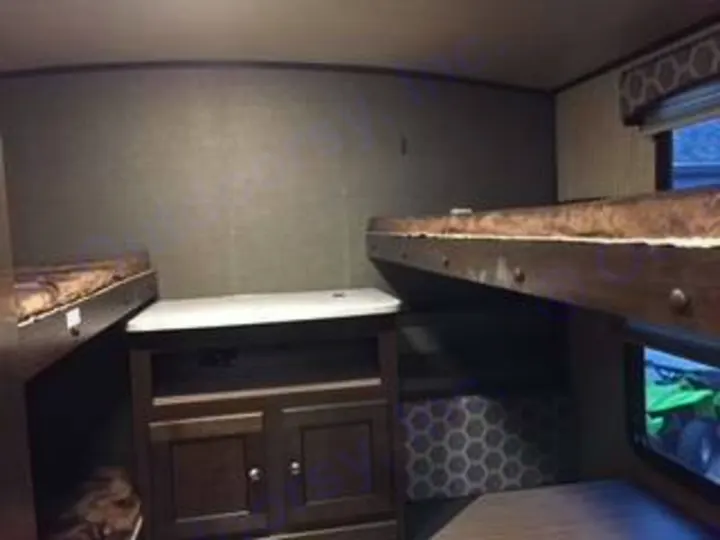 Explore this RV rental's cozy bunk bed area. Dark wood bunks and a central cabinet offer sleeping and storage inside.. Cruiser RV Shadow Cruiser 2019