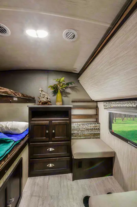 Cozy RV rental interior with bunk beds, storage, and a dinette by the window, offering compact comfort for travel.. Cruiser RV Shadow Cruiser 2019