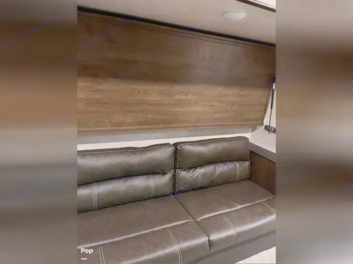 RV rental interior: Comfortable brown sofa below a wall-mounted murphy bed, ideal for a flexible living space.. Keystone RV Cougar 2021